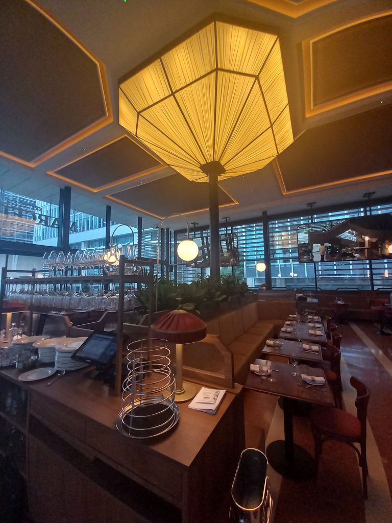 Bespoke feature ceiling light lit up over restaurant seating and planters