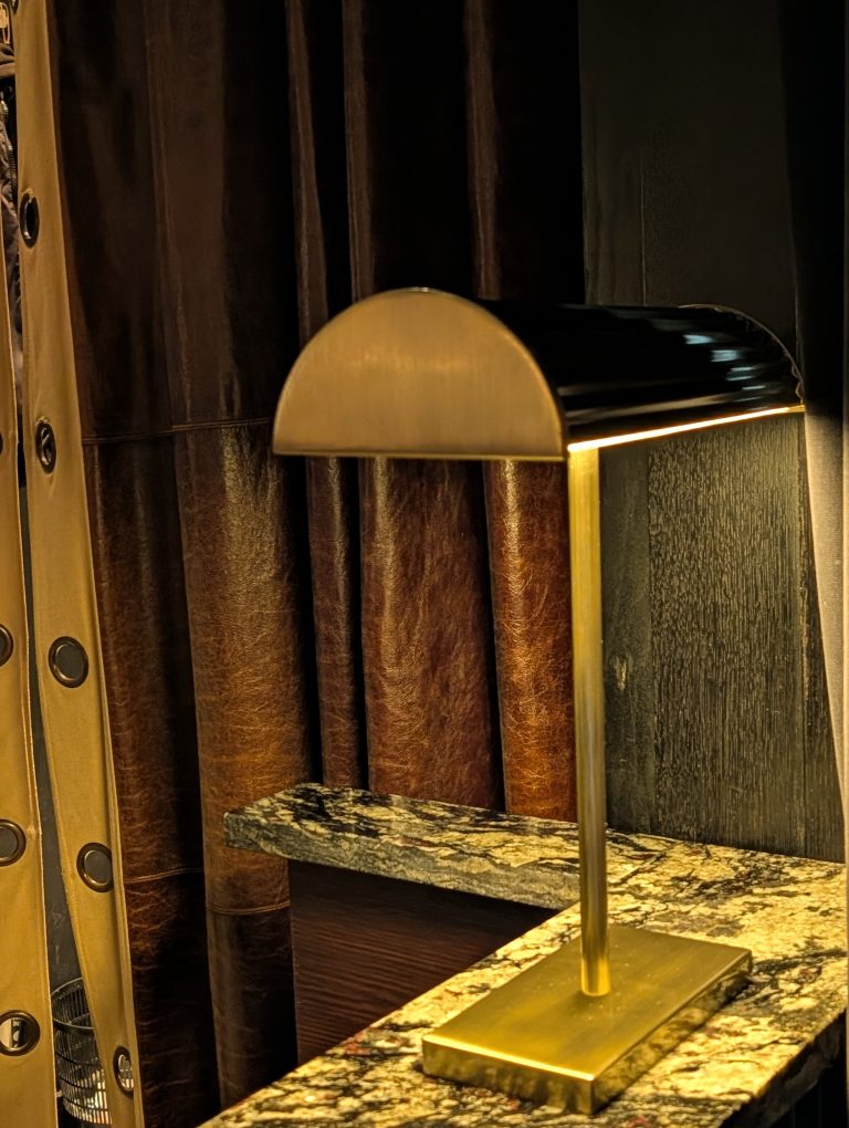 Bespoke antique brass table lamp with half-round shade on a marble maître d' counter